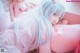 A woman with long blue hair laying on a pink couch.
