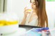 A woman in a white dress drinking from a glass.