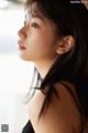 A woman with long black hair looking out a window.