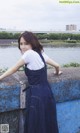 A woman leaning against a wall by the water.