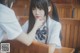 A woman in a school uniform sitting at a table.