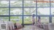 Two women standing in front of a large window looking out at trees.