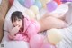 A woman laying on a bed surrounded by balloons.