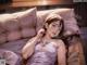 A woman laying on top of a bed next to pillows.