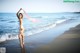 A woman in a white bathing suit standing on the beach.