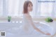 A woman in a white dress sitting in a bathtub.