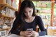 A woman sitting at a table looking at her phone.