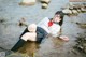 A woman in a school uniform is sitting in the water.