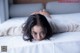 A woman laying on a bed with her head on the pillow.