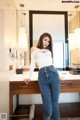 A woman standing in front of a mirror in a bathroom.