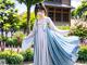 A woman in a blue and white dress standing in a garden.