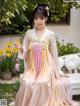 A woman in a pink and yellow hanbok sitting on a bench.