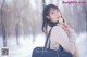 A woman is holding a black bag in the snow.