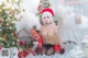 A woman in a santa hat sitting in front of a Christmas tree.