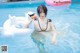 A woman in a black bikini holding an inflatable swan in a pool.