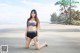 A woman in a bikini sitting on the beach.