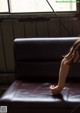 A woman sitting on a couch in front of a window.